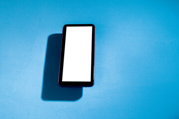 Smartphone with white screen on top of blue table. Cell phone concept. White screen concept. png