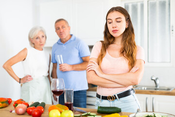 Elderly parents scold adult daughter in modern kitchen
