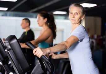 Mature woman exercising on an elliptical trainer in the gym