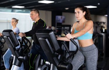Fototapeta na wymiar Fit young woman working out at elliptical machine in gym