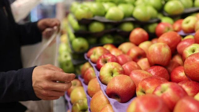 Man choosing apples in a grocery store. Close up of a mans hand with apples green and red. Choosing good harvest 