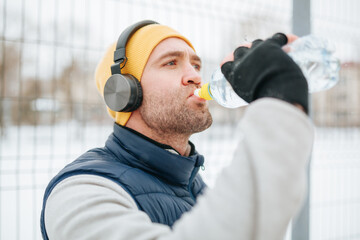 Wintertime Hydration A determined runner, headphones on, He is seen taking a quick break to hydrate...