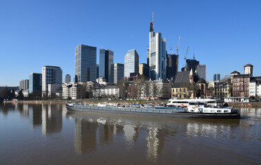 Obraz premium Rhine cargo ship on the river Main with the Frankfurter skyscraper landscape in the background.