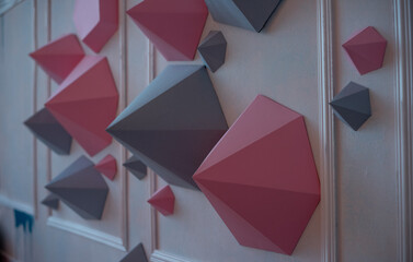 Abstract background of paper polygons of gray, pink, different shapes on a white wall. Creative...