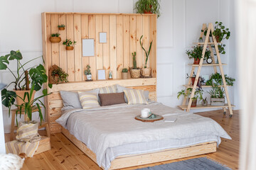Bedroom in rustic style. Scandinavian interior with large bed with wooden wall. Staircase with...