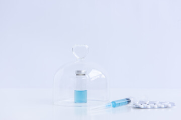 On white isolated background lie a syringe with medicine, a vial with a blue vaccine against viruses, pills for flu, colds. Medical preparations for the fight against the epidemic. Mock up, copy space