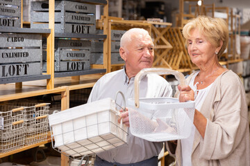 Fototapeta na wymiar Mature married couple makes choice of buying a basket for a country house