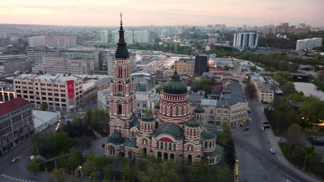 Arc flight around Holy Annunciation Cathedral with evening sunset scenic cloudscape. Aerial view Kharkiv city orthodox church in downtown, Ukraine