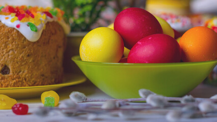 Painted Easter eggs in a green glass bowl on a wooden table