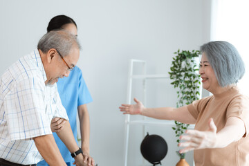 Asian nurse support senior elderly male, Asian older aged man doing physiotherapist in home living room using walker workout exercise for patient with caregiver in health insurance nursing care