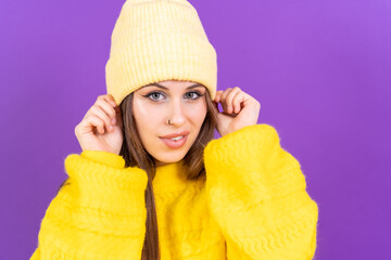 Close up portrait of young caucasian woman in yellow sweater isolated on yellow background, wearing wool cap