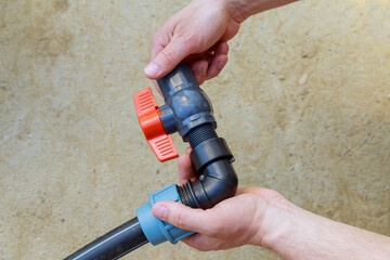 A plumber installs a ball valve for water on a polyethylene pipe.