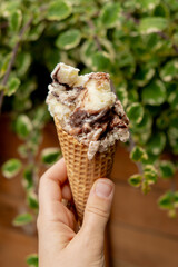 Female hand holding delicious american vanilla chocolate ice cream. Tasty homemade icecream Gelato in the waffle cone. Gluten free vegan dairy free ice cream. 