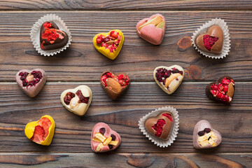 chocolate sweets in the form of a heart with fruits and nuts on a colored background. top view with space for text, holiday concept