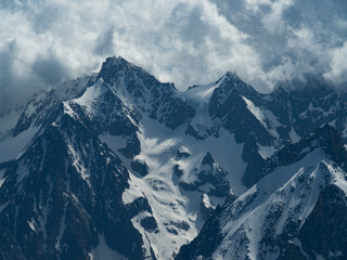 Obraz premium Majestic view of Mont Blanc near Chamonix, showcasing its snow-covered slopes, rugged peaks, and deep crevasses. Clouds hover over the valleys, adding to the breathtaking alpine scenery