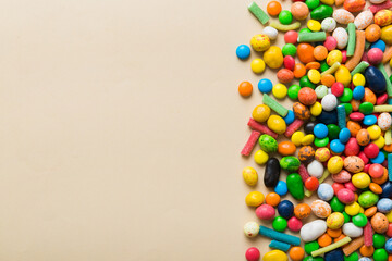 Obraz premium Mixed collection of colorful candy, on colored background. Flat lay, top view. frame of colorful chocolate coated candy