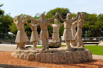 A stone carving that shows a circle of men and women holding hands pointing upwards apparently...
