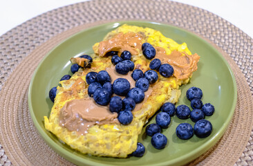 Stuffed omelette. Fried omelette with peanut butter and blueberries on a plate. Sweet and healthy breakfast dish
