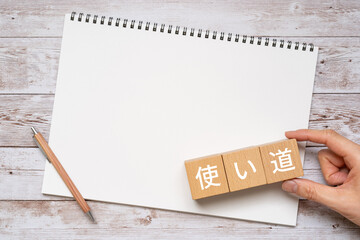 使い道と書かれたブロック、ノート、ペン、手
