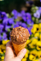 Female hand holding delicious american vanilla chocolate ice cream. Tasty homemade icecream Gelato in the waffle cone. Gluten free vegan dairy free ice cream. 