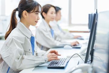 オフィスでデスクワークをする作業服を着た女性