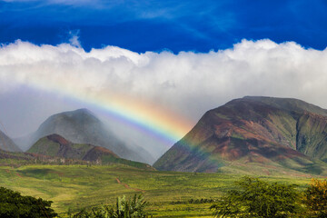 Gorgeous blue sky with clouds featuring a beautiful rainbow across west maio mountains.