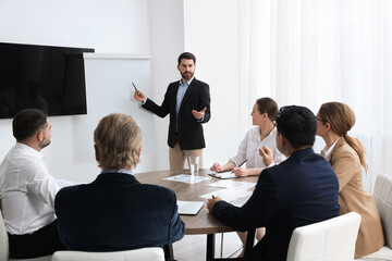 Business conference. Group of people listening to speaker report near tv screen in meeting room