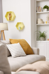 Spring atmosphere. Soft sofa, lamp and shelves with stylish accessories in room