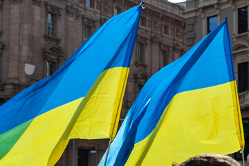 Flag with yellow and blue striped colors of Ukraine waving in the wind with a blue sky and sun.