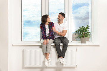 Happy couple sitting on windowsill in new apartment. Moving day