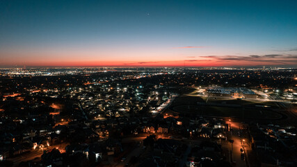 Fototapeta premium sunset over the city: Blue hour where the sun sets and the night begins, the streets and the city are illuminated