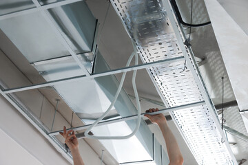 Worker installing metal frame indoors, closeup. Suspended ceiling