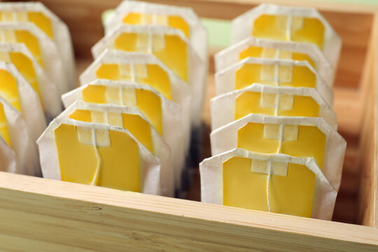 Paper tea bags with tags in wooden box, closeup