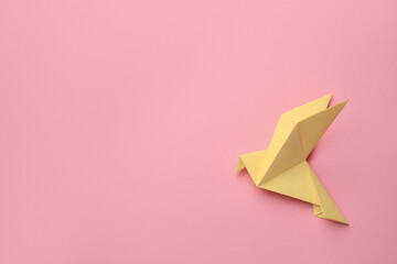 Beautiful yellow origami bird on pink background, top view. Space for text