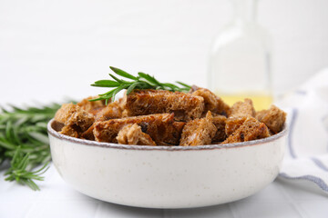 Crispy rusks with rosemary on white tiled table, closeup