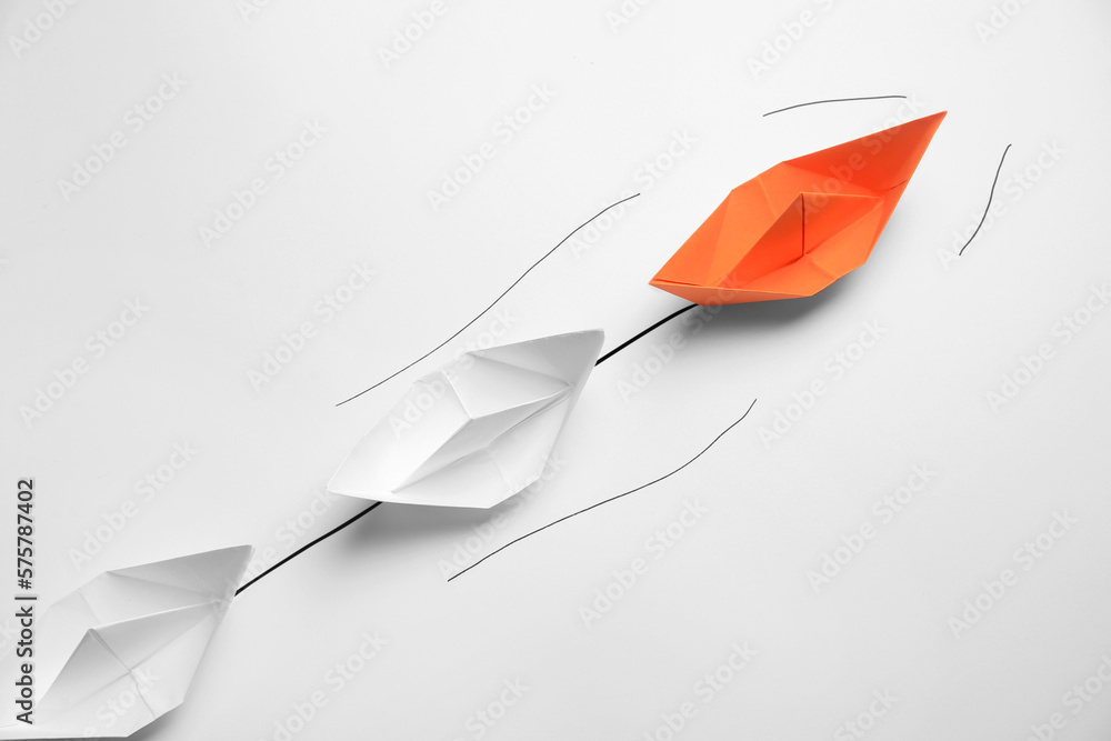 Wall mural Group of paper boats following orange one on white background. Leadership concept