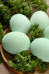 Turquoise Easter eggs painted with natural dye and curly parsley on table, closeup