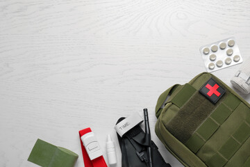 Military first aid kit, tourniquet, pills and elastic bandage on white wooden table, flat lay....