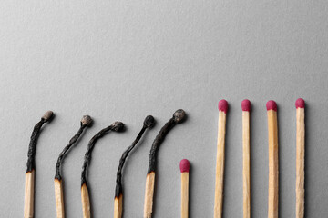 Burnt and whole matches on light grey background, flat lay. Space for text