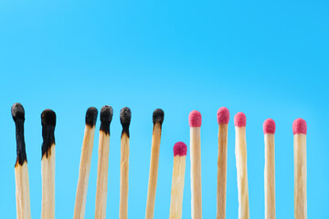 Burnt and whole matches on light blue background. Space for text