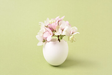 Spring Flowers bouquet in eggshell. Easter greeting card. Light green background, copy space. Spring time concept.