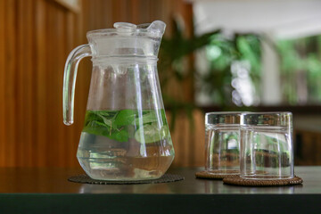 Detox water made of cucumber, lime and mint leaves in jug in the lounge area