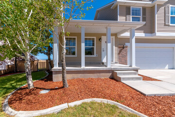 Exterior view of a home with porch and white front door and garage door. The two storey house also...