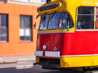 Front of a retro tram with headlights on a city street.