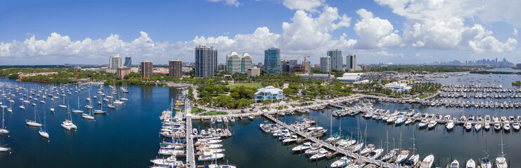 Miami Florida coastal landscape with condominiums and boats against blue sky. Aerial view of city skyline with buildings overlooking yachts at the manmade inland water channel.