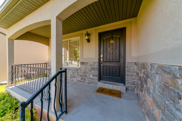Front view of a home with an open porch and dark gray front door at the entrance. Stone wall,...