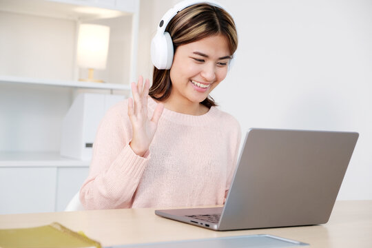 Young asian woman with headphones while make video conference by laptop computer