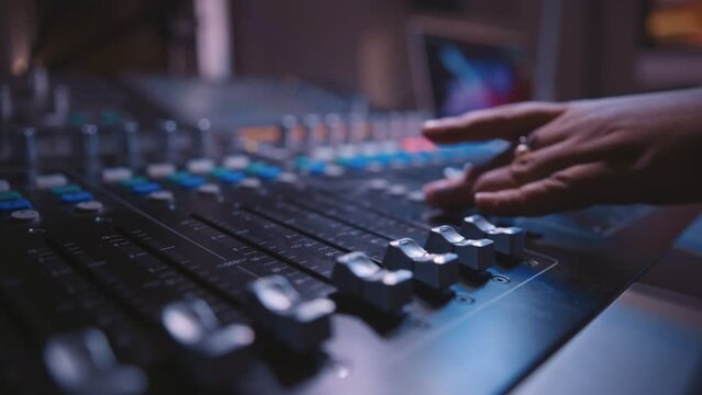 sound engineer fingers on audio mixing console fader in recording, broadcasting studio
