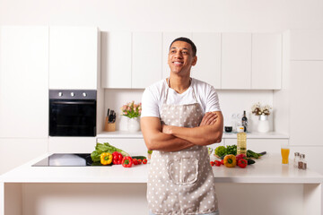 African guy in apron stands in the kitchen with groceries and smiles, American male cook near the...