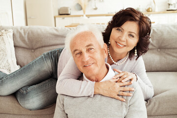 Portrait of cute happy Caucasian couple of retired husband and wife hugging indoors.